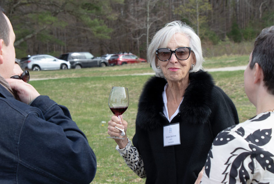 Barbara Senchak speaks with the Quinns and smiles for the camera at the New Hampshire Benefit cocktail hour in May 2022. She is holding a glass of wine.