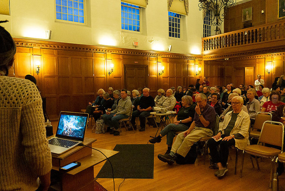 A small, seated audience listens to presentations during MacDowell Downtown