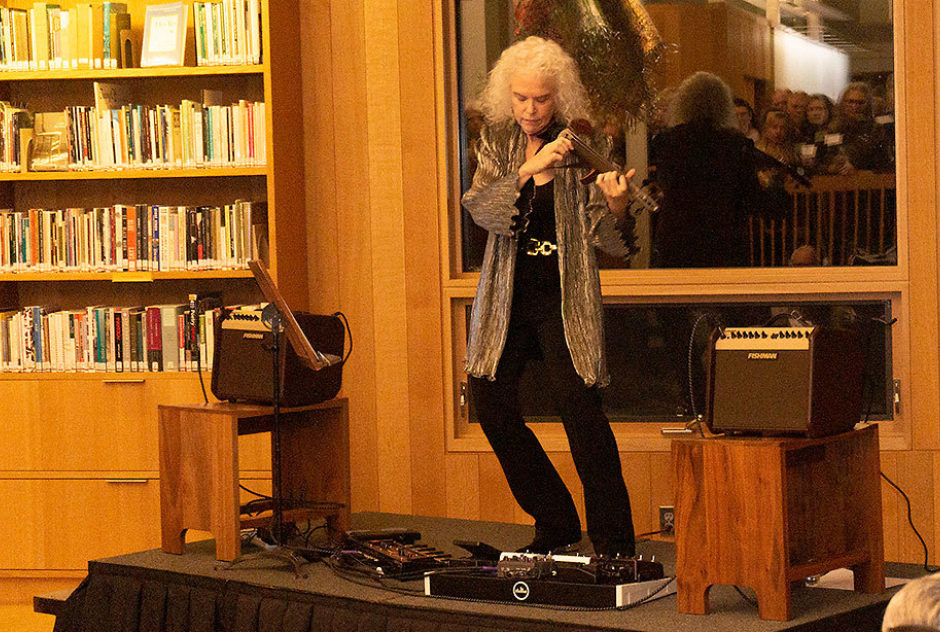 Martha Mooke performs on a small stage in the James Baldwin Library for the benefit attendees