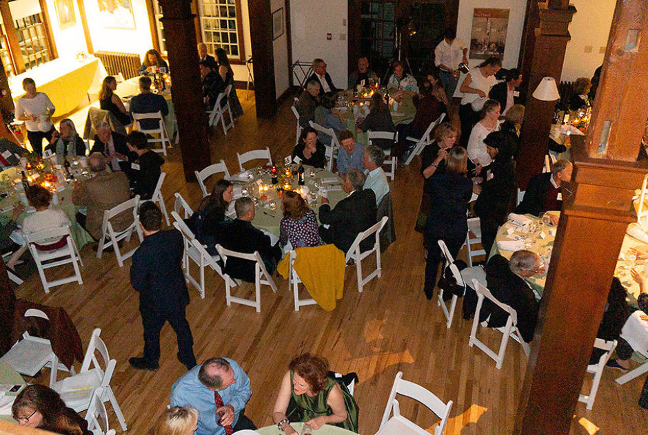 New Hampshire Benefit attendees sit and mingle around tables. Photo taken from the balcony in Bond Hall, overlooking the party
