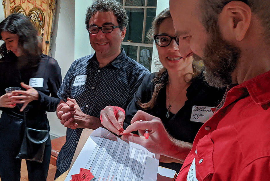 Fellows gather around a sheet of paper for a silent auction
