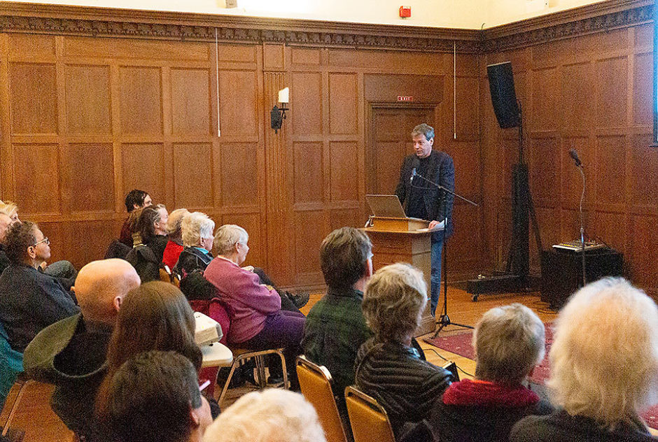 Fellow Michael Moore presents at a podium during a MacDowell Downtown event