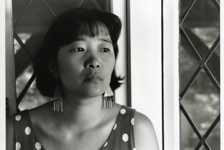 Portrait of Katherine Min. She sits in a windowsill and looks off the the side