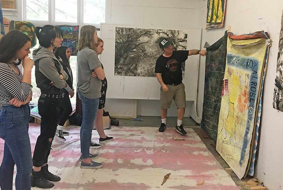 Paul Collins shows a group of high school students a piece he is working on during a studio visit