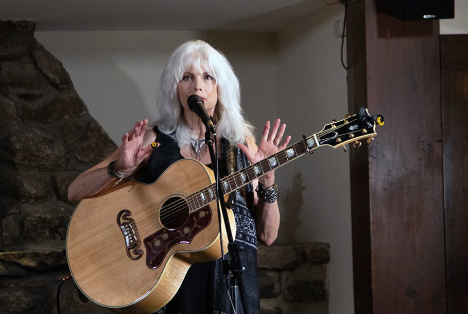 Emmylou Harris performs on stage in Bond Hall. She sings and plays the acoustic guitar,