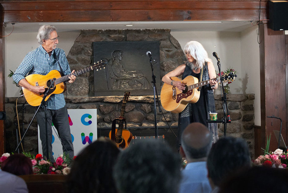 John Leventhal and Emmylou Harris perform on stage in Bond Hall. They are both playing the acoustic guitar.