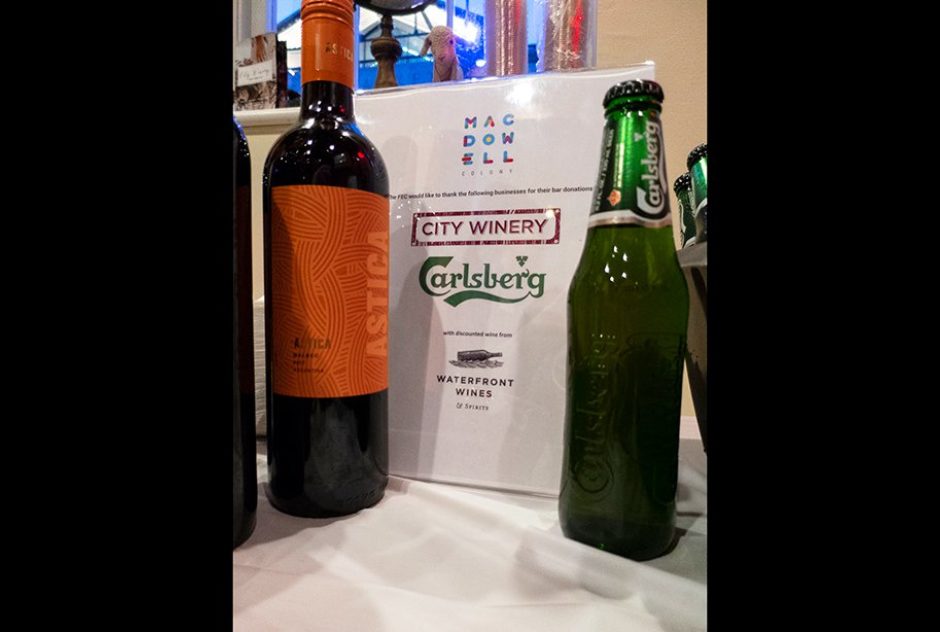 A wine bottle and a beer bottle sit next to a sign that indicates the drink menu for the evening