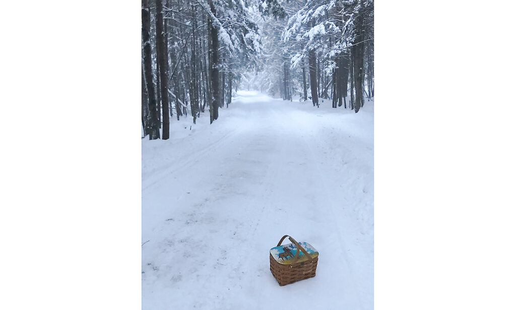 A MacDowell lunch basket in foreground on a snow-covered road
