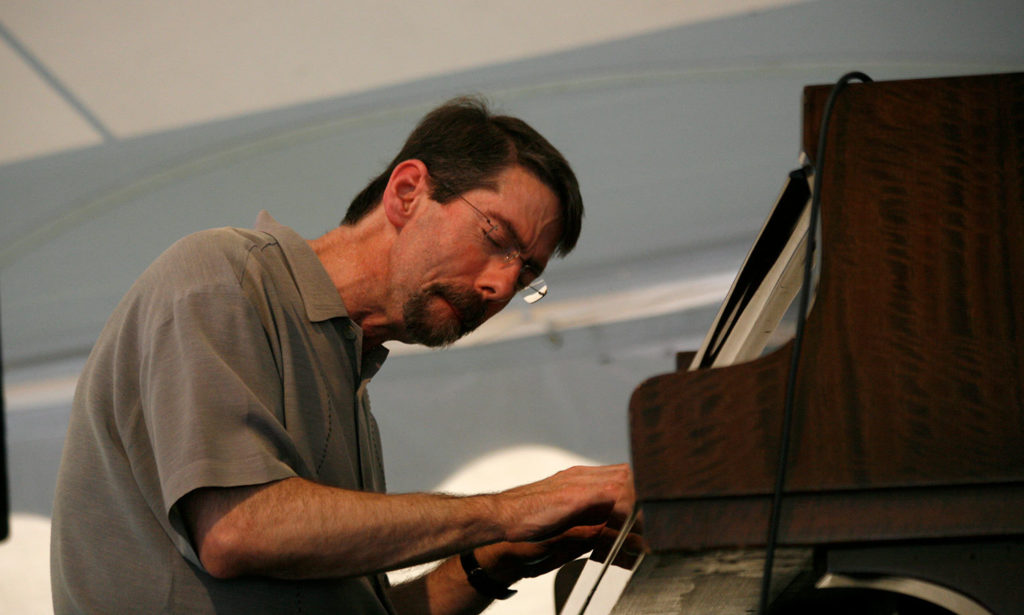 Fellow Fred Hersch at a piano. His eyes are closed as he plays
