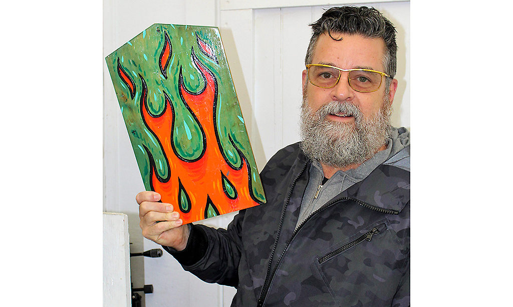 Fellow Mark Dean Veca revisits Firth Studio in 2019. He is holding up a piece of artwork featuring cartoon flames