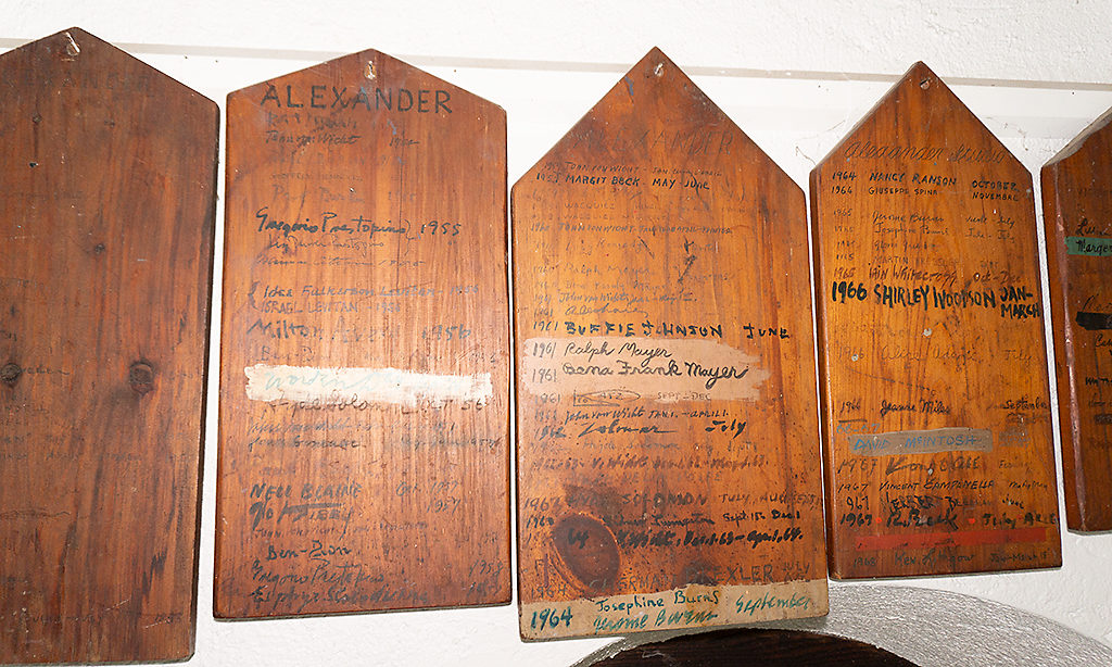 Wooden plaques known as the MacDowell Tombstones hanging on a wall. The Tombstones are host to the names of Fellows that have stayed in the studio