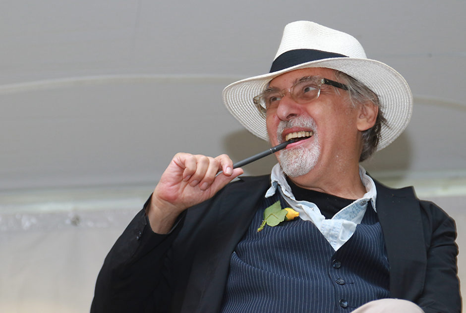 Art Spiegelman smiles brightly. He holds a pen to his mouth.
