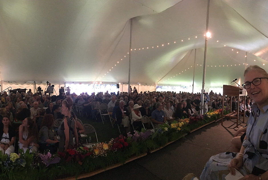 The Medal Day crowd from the perspective of the stage. A large crowd sits in rows of chairs under a large tent, awaiting the start of the ceremony.