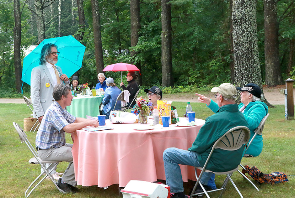 People gather around tables with brightly colored tablecloths, enjoying the Medal Day picnic