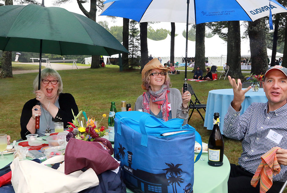 Picnickers smile joyfully, enjoying their lunch at a table