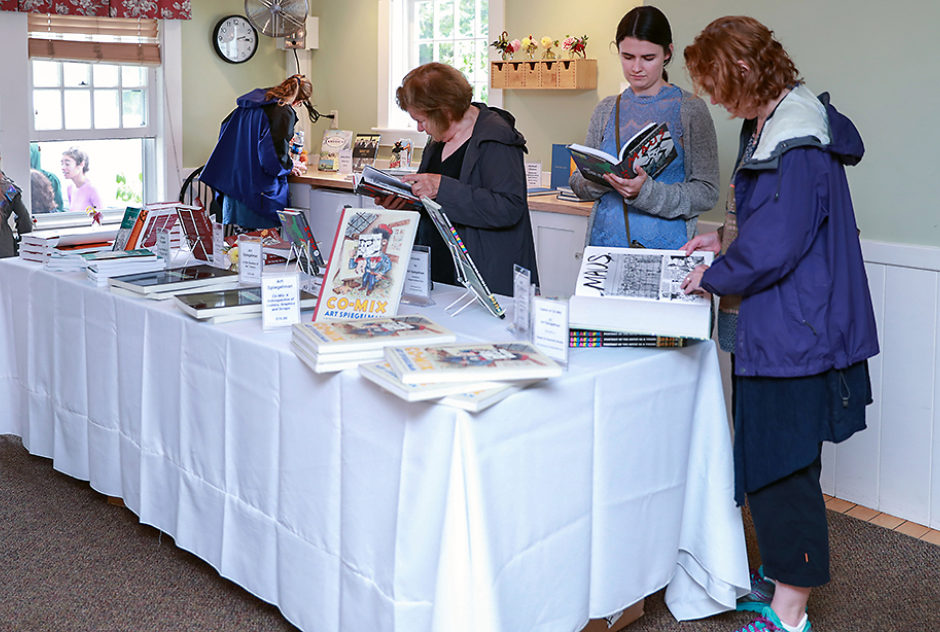 A group of people look through books at the Medal Day shop