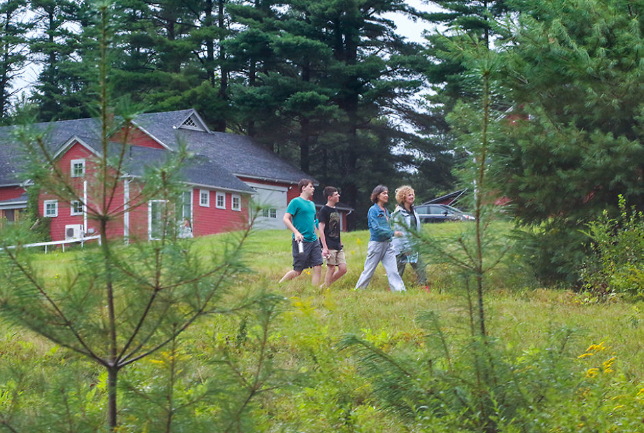 A small group of people walk across the lawn while touring studios