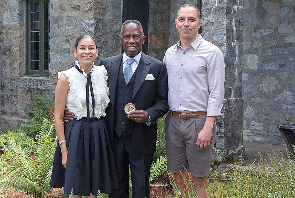 Charles Gaines holds his Medal and poses with two other VIPs