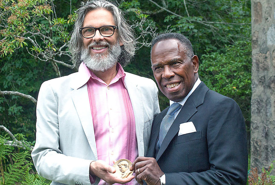 Michael Chabon and Charles Gaines pose together and hold the Edward MacDowell Medal between them.