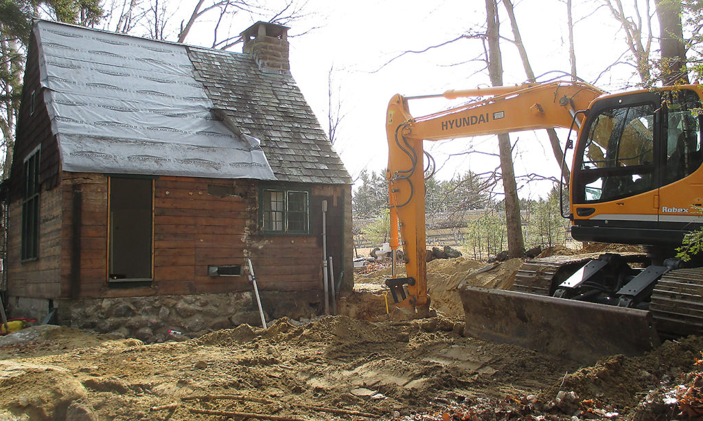 Exterior shot of Delta Omicron studio under renovation. A backhoe digs into the ground around the studio.