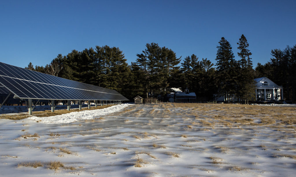 Side view of the solar array in the large field behind Bond Hall. Bond Hall can be seen in the distance on the far side of the field. There is a thin layer of snow on the ground