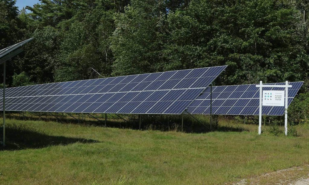 The solar array located just off of High Street. Next to the array is a sign signifying the entrance to MacDowell grounds