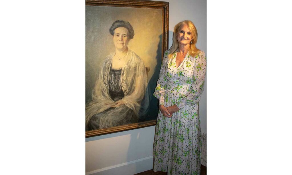 Christine Fisher stands with a life-size portrait of Marian MacDowell painted by Orlando Rouland.