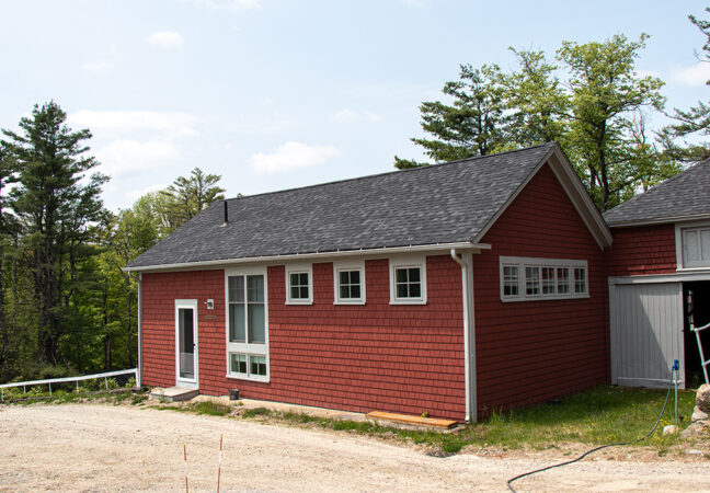 Front of Eastman studio in spring time. The red building sits right against a dirt road and is connected to a large barn