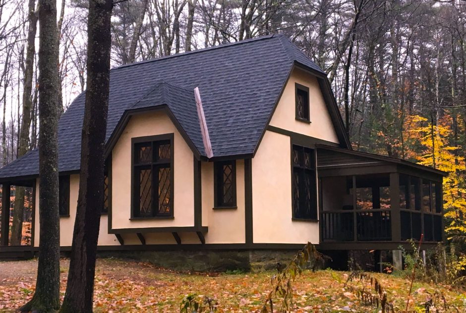 Garland Studio on a rainy day in fall. The sky is gloomy and the air is foggy. The dense pine forest surrounding the building has pops of brightly colored leaves.