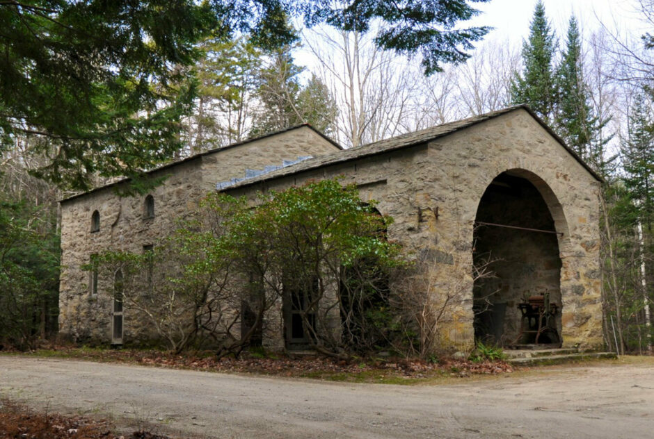 Alexander Studio in early fall. The stone building features large arches and is nestled into a dense forest