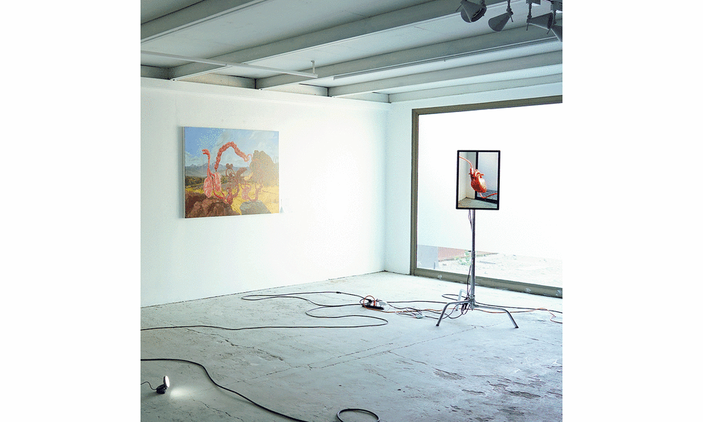 A white exhibition space with two pieces of artwork. One on the wall, the other displayed on a stand in the center of the room.